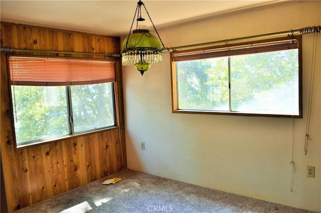 carpeted empty room featuring wooden walls