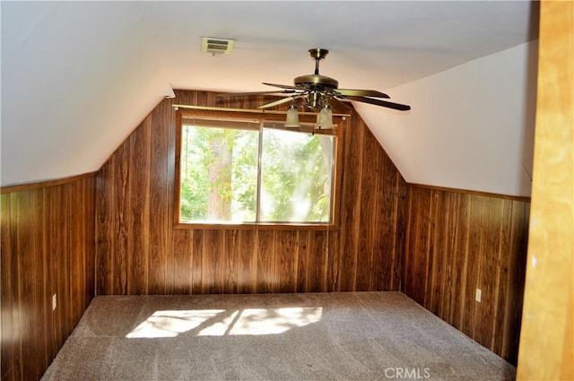 additional living space featuring carpet, ceiling fan, wooden walls, and vaulted ceiling