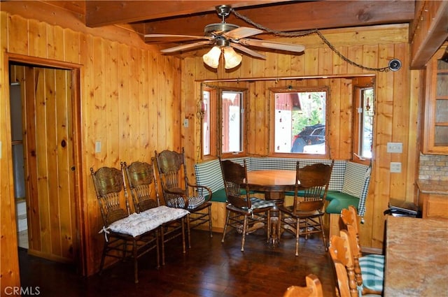 sitting room with beamed ceiling, ceiling fan, wood walls, and dark hardwood / wood-style flooring