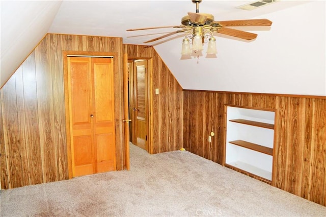 additional living space with carpet, wooden walls, ceiling fan, and lofted ceiling