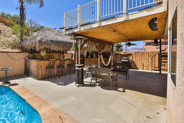 view of patio featuring a fenced in pool, ceiling fan, and a bar