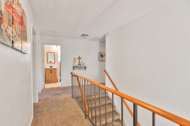 hallway with light carpet and a textured ceiling