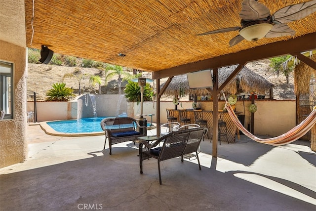 view of patio / terrace featuring pool water feature, ceiling fan, a fenced in pool, and an outdoor bar