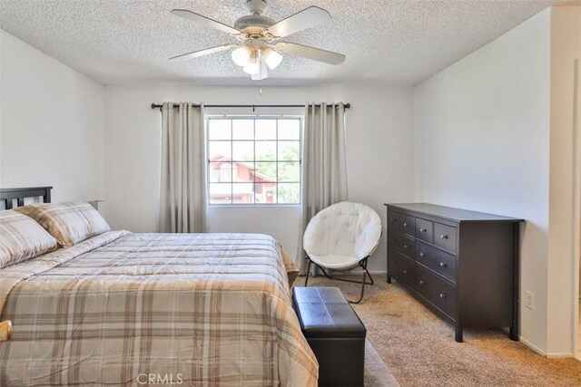 carpeted bedroom featuring ceiling fan and a textured ceiling