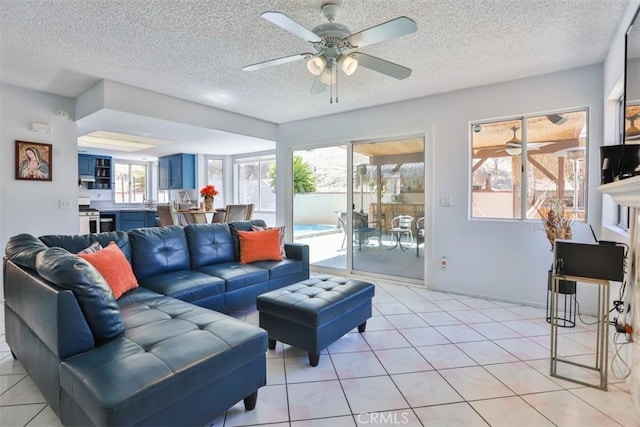 living room featuring ceiling fan, light tile patterned floors, and a textured ceiling