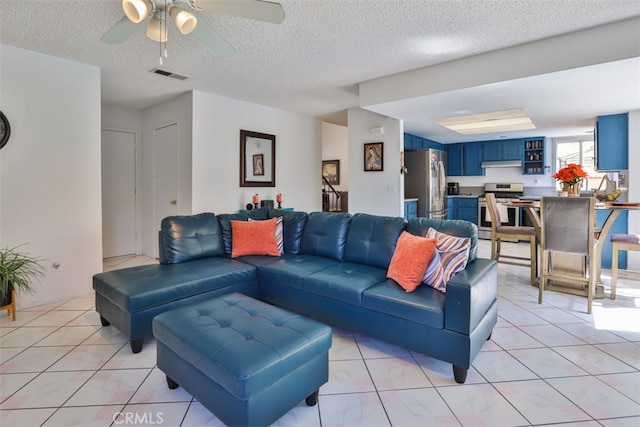 living room with ceiling fan, light tile patterned floors, and a textured ceiling