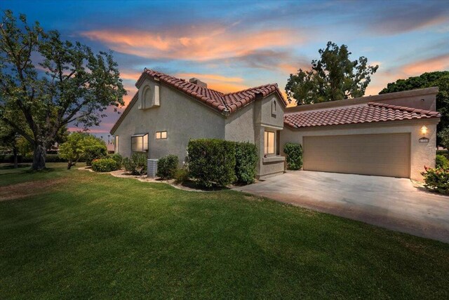 mediterranean / spanish-style house featuring a garage and a lawn