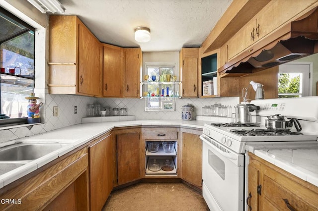 kitchen featuring tile countertops, white gas range oven, custom range hood, and backsplash