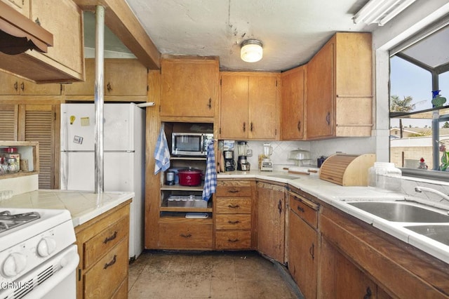 kitchen with white appliances, tile countertops, and sink