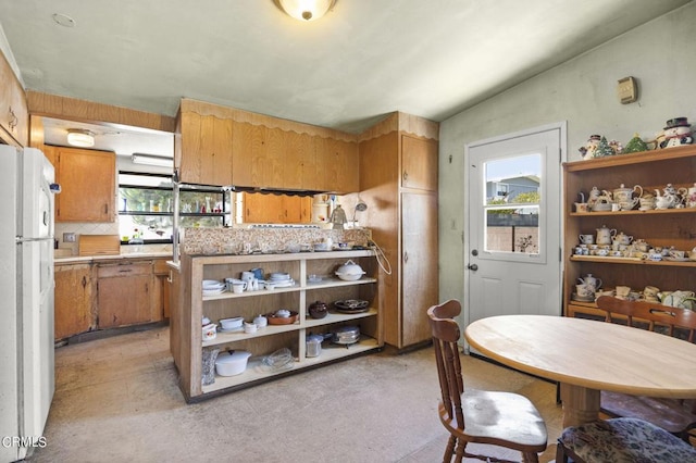 kitchen with decorative backsplash, vaulted ceiling, and white fridge