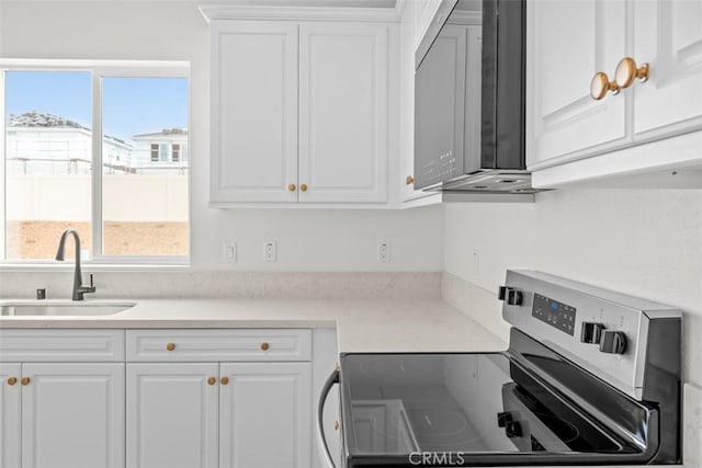 kitchen with stainless steel electric stove, sink, and white cabinets