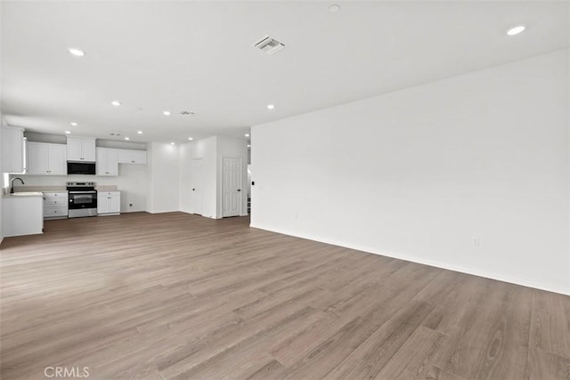 unfurnished living room with light hardwood / wood-style floors and sink