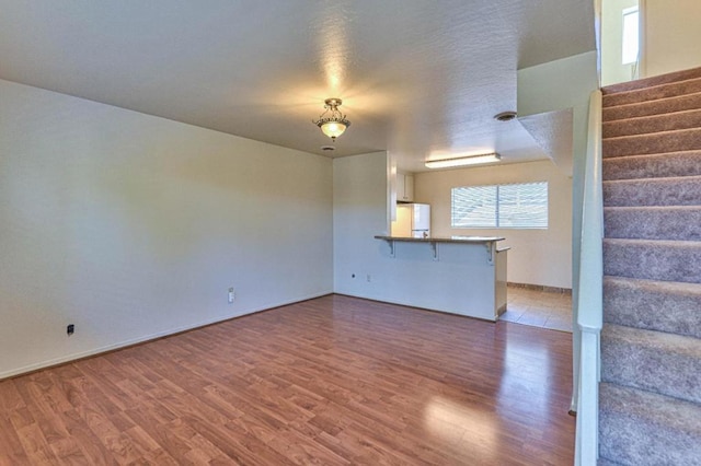 unfurnished living room with a textured ceiling and dark wood-type flooring