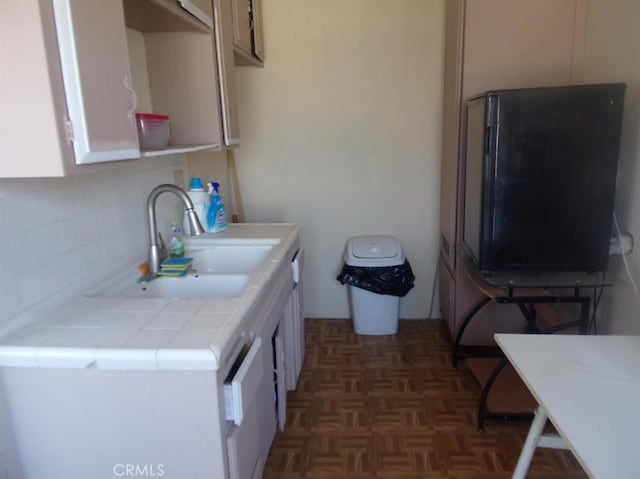 kitchen featuring sink, refrigerator, tile countertops, and dark parquet flooring