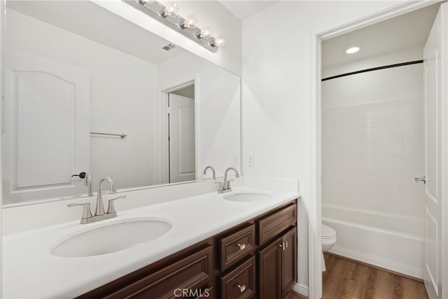 full bathroom with wood-type flooring, bathing tub / shower combination, vanity, and toilet