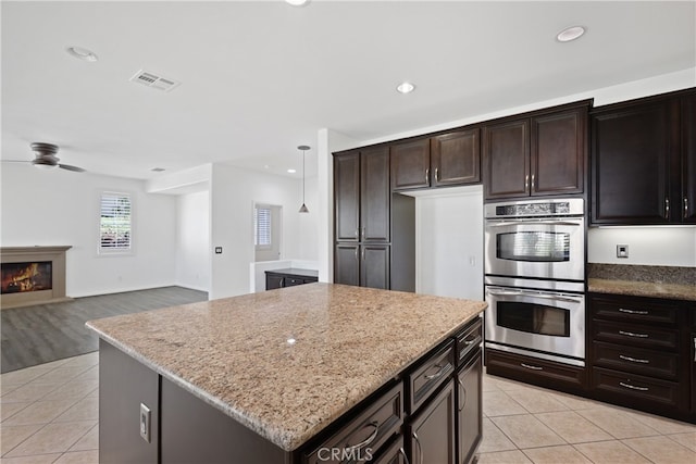 kitchen with a center island, hanging light fixtures, light tile patterned floors, ceiling fan, and double oven