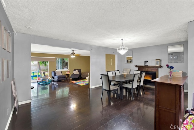 dining room featuring ceiling fan with notable chandelier, a textured ceiling, and dark hardwood / wood-style flooring