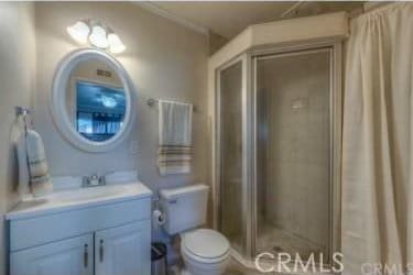 bathroom with vanity, toilet, ornamental molding, and tiled shower