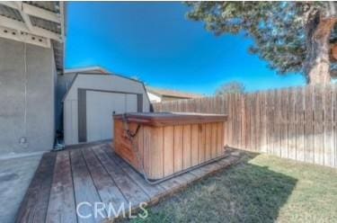 exterior space featuring a hot tub, a storage unit, and a wooden deck