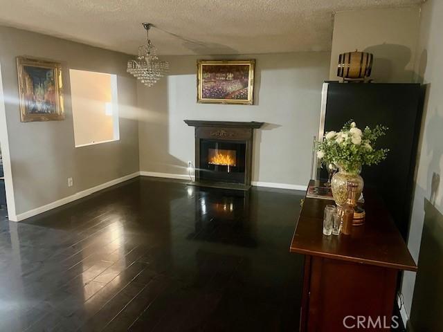 living room featuring a textured ceiling, dark hardwood / wood-style floors, and a notable chandelier