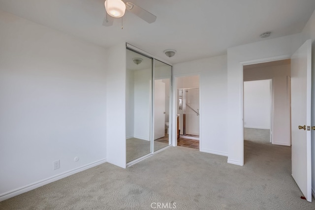 unfurnished bedroom with baseboards, carpet floors, connected bathroom, ceiling fan, and a closet