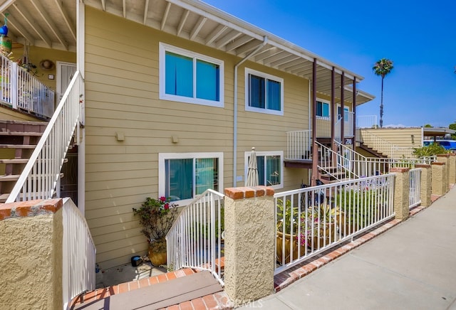 rear view of property with fence and stairway