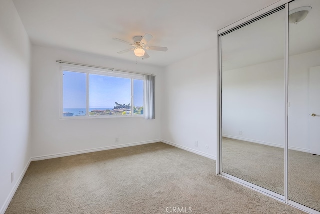 unfurnished bedroom with ceiling fan, light colored carpet, and a closet