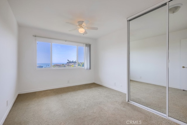 unfurnished bedroom with baseboards, carpet floors, ceiling fan, and a closet