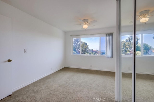 carpeted empty room featuring ceiling fan and a wealth of natural light