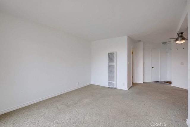 empty room featuring carpet floors, a heating unit, baseboards, and ceiling fan