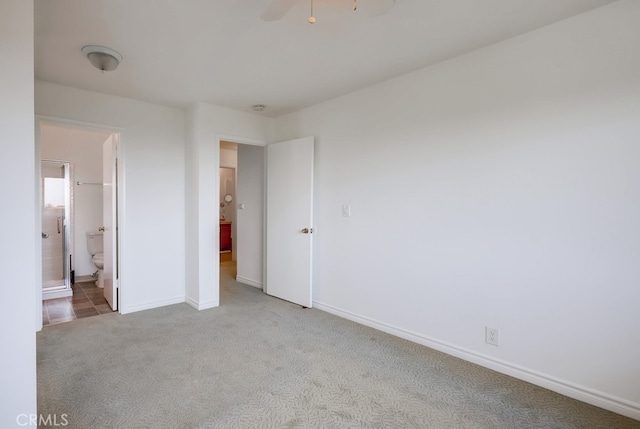 unfurnished bedroom with baseboards, ensuite bath, and light colored carpet