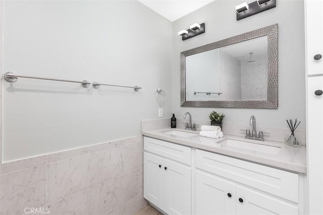 full bathroom with double vanity, a sink, and tile walls