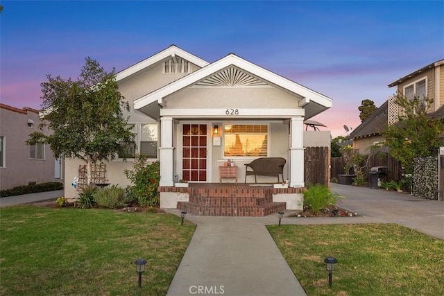 view of front of house featuring a porch, a front lawn, and stucco siding