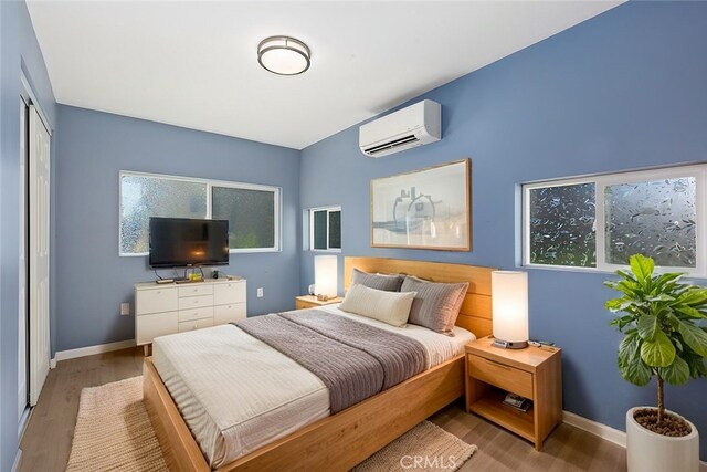 bedroom featuring wood-type flooring, an AC wall unit, and a closet