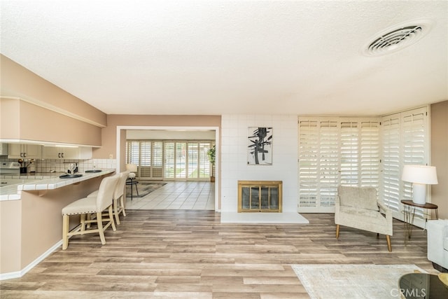 unfurnished room featuring brick wall, a textured ceiling, and light wood-type flooring