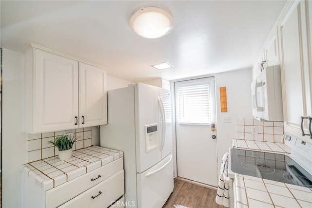 kitchen with decorative backsplash, hardwood / wood-style flooring, tile counters, and white appliances