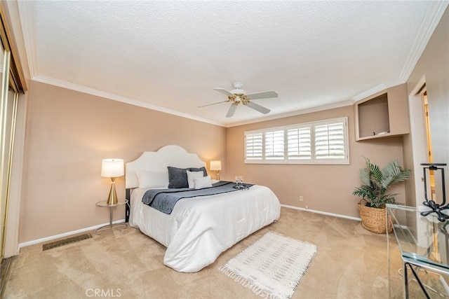 carpeted bedroom featuring a textured ceiling, crown molding, a closet, and ceiling fan