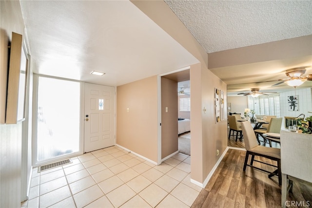 foyer entrance with light wood-type flooring, ceiling fan, and a textured ceiling