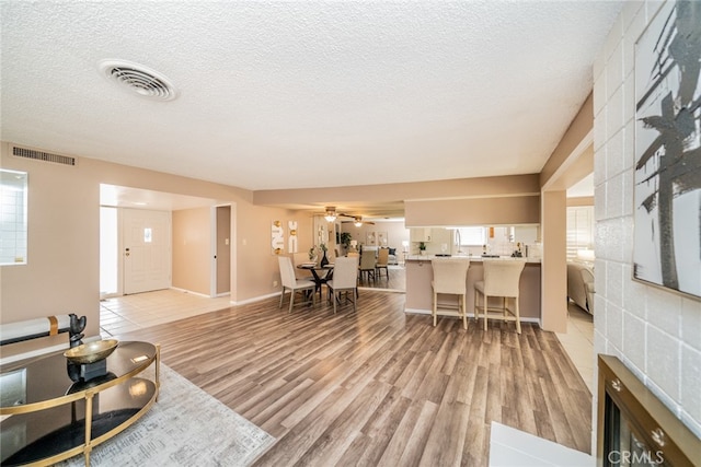 living room featuring a textured ceiling, ceiling fan, and light hardwood / wood-style floors