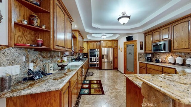 919 Venus Way, Crestline, CA 92325 - kitchen with brown cabinetry, appliances with stainless steel finishes, light stone countertops, a tray ceiling, and open shelves