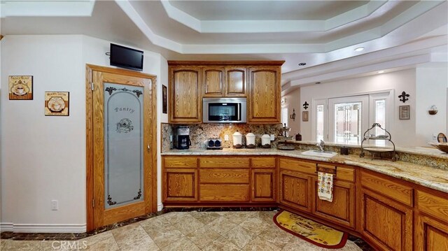 919 Venus Way, Crestline, CA 92325 - kitchen with a raised ceiling, stainless steel microwave, brown cabinets, a sink, and backsplash