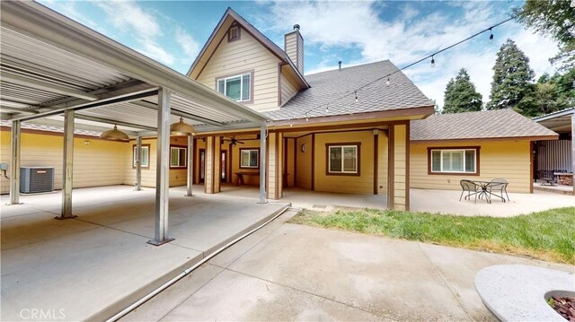 919 Venus Way, Crestline, CA 92325 - back of property with a shingled roof, central AC unit, a patio, a chimney, and an attached carport