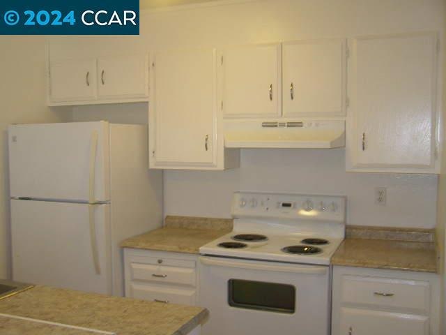 kitchen featuring white cabinetry, white appliances, and wall chimney exhaust hood