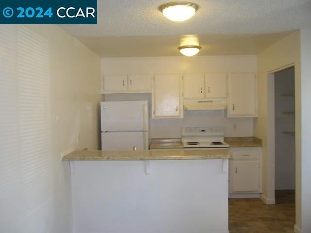 kitchen with stove, white cabinetry, white fridge, and tile patterned flooring