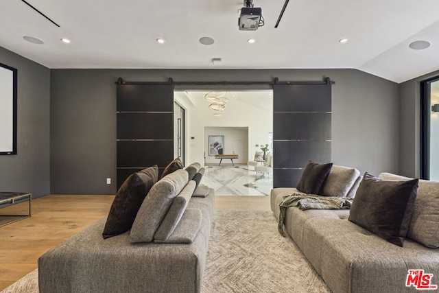 home theater room featuring a barn door, lofted ceiling, and light hardwood / wood-style flooring