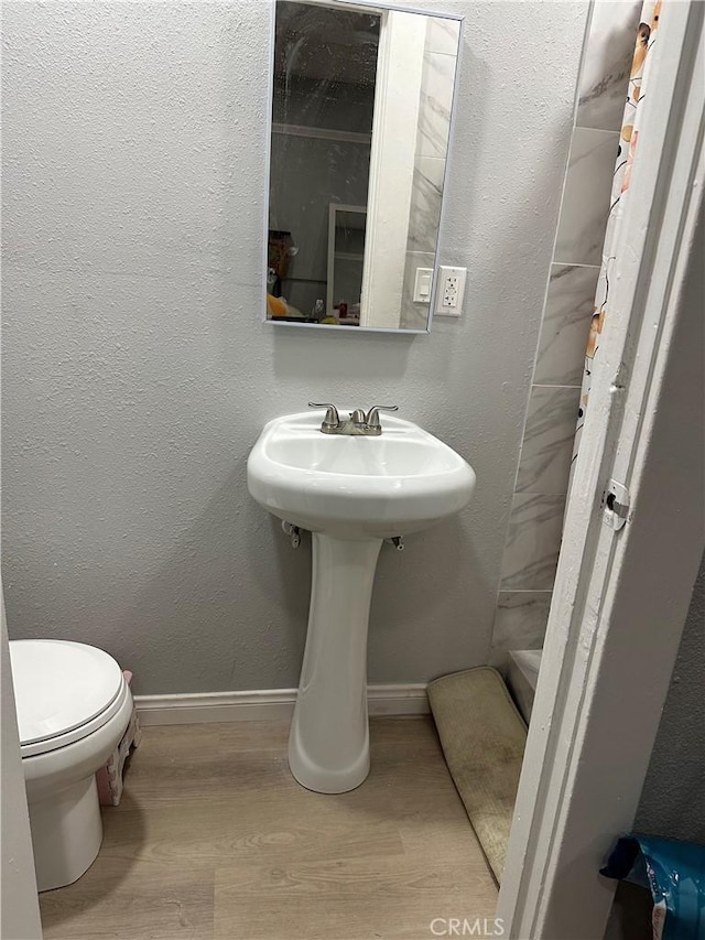 bathroom featuring a shower, hardwood / wood-style floors, and toilet