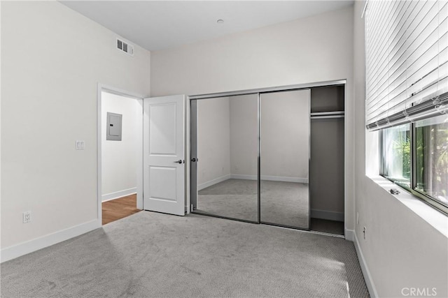 unfurnished bedroom featuring light carpet, electric panel, and a closet