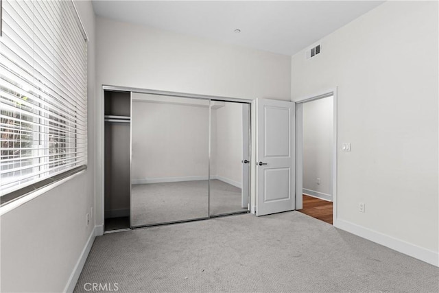 unfurnished bedroom featuring light carpet and a closet