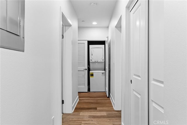 hall with hardwood / wood-style flooring and stacked washer and clothes dryer