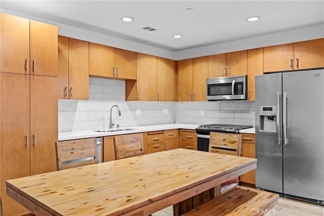 kitchen featuring tasteful backsplash, appliances with stainless steel finishes, sink, and light wood-type flooring